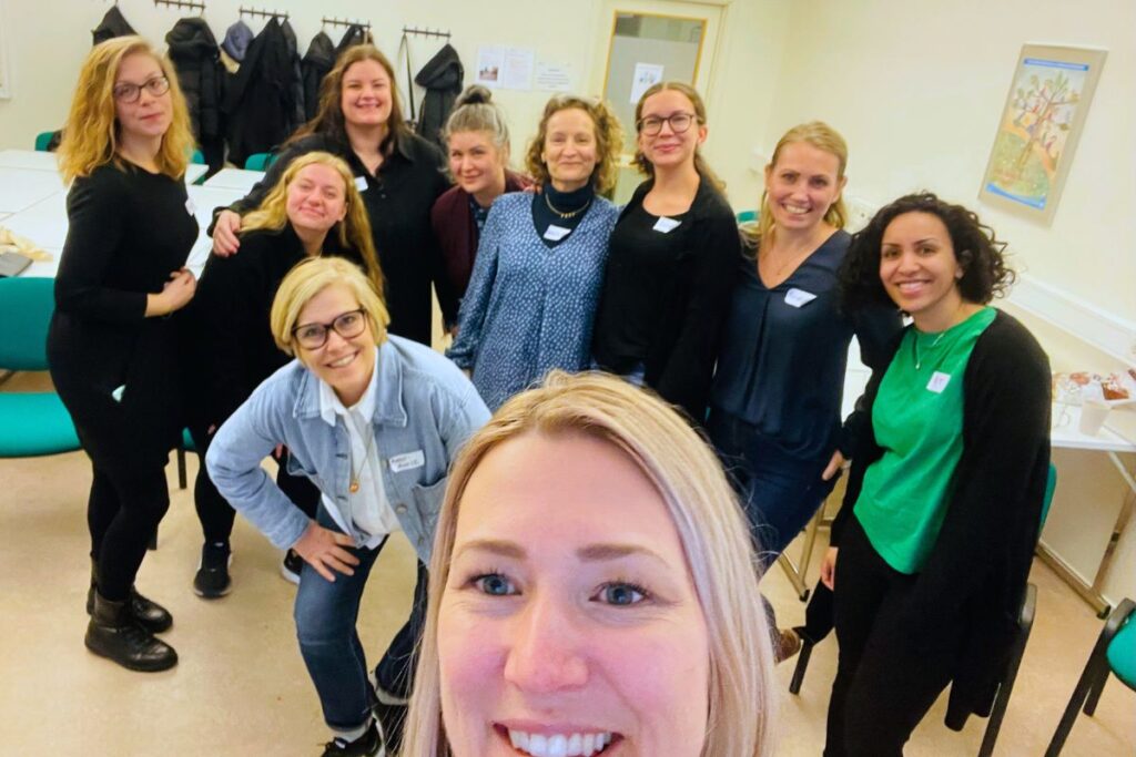 Josephine tar en selfie med en grupp deltagare i MI utbildning i bakgrunden